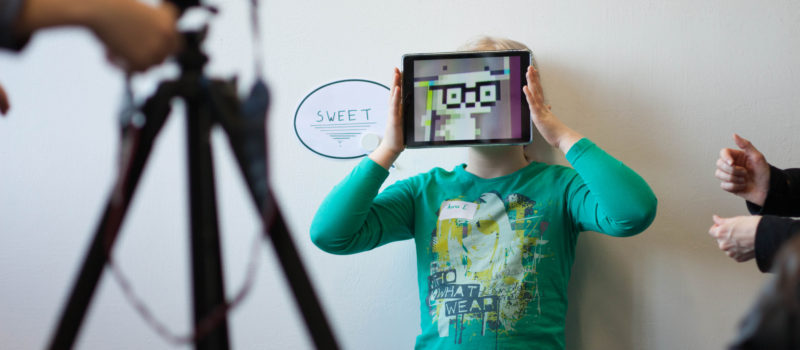 Ein Kind hält sich bei den Aufnahmen zum Projekt "Museum macht stark" ein Tablet vor das Gesicht
