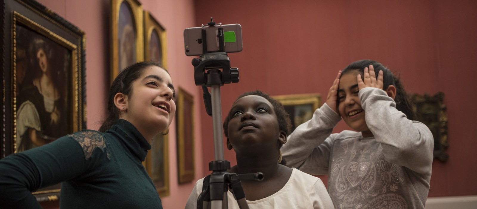 Drei Mädchen machen in einem Museum Fotos mit einem Handy