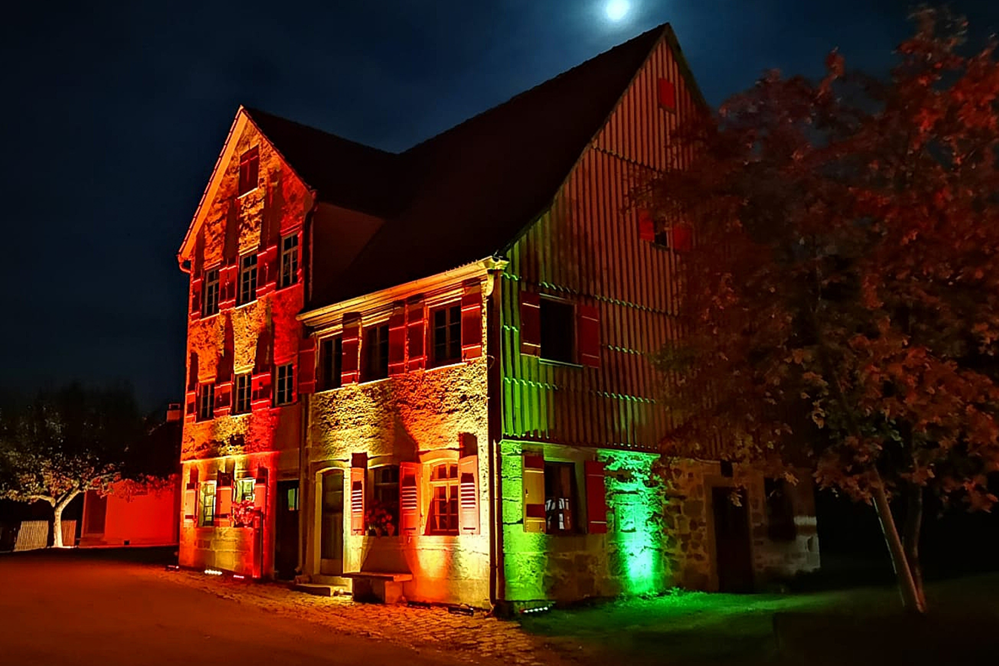 Historisches Wohnhaus bei Nacht mit bunter Beleuchtung in Wackershofen