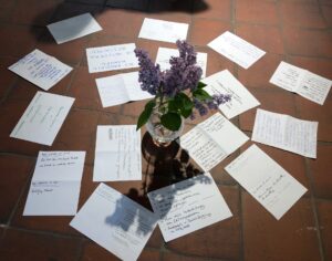 Ausgefüllte Zettel liegen um eine Blumenvase auf dem Boden