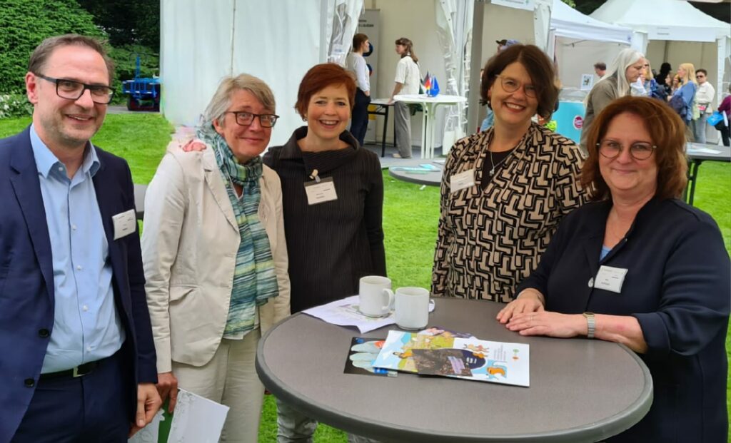 Fünf Personen stehen um einen Stehtisch