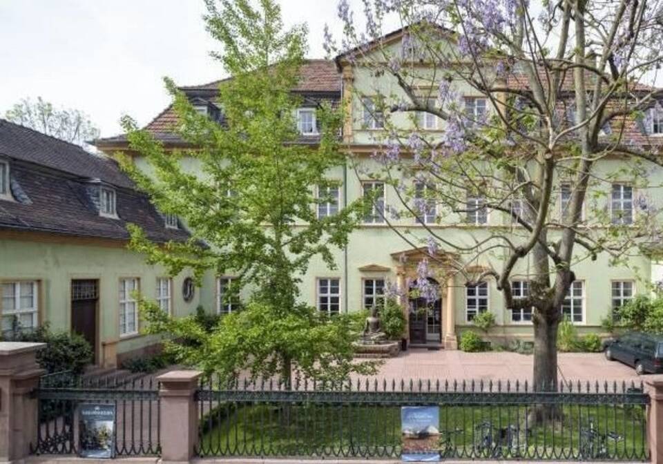Ansicht des Museumsgebäudes: Idyllisches barockes Palais mit einem idyllischen mit Bäumen bepflanztem Vorgarten.